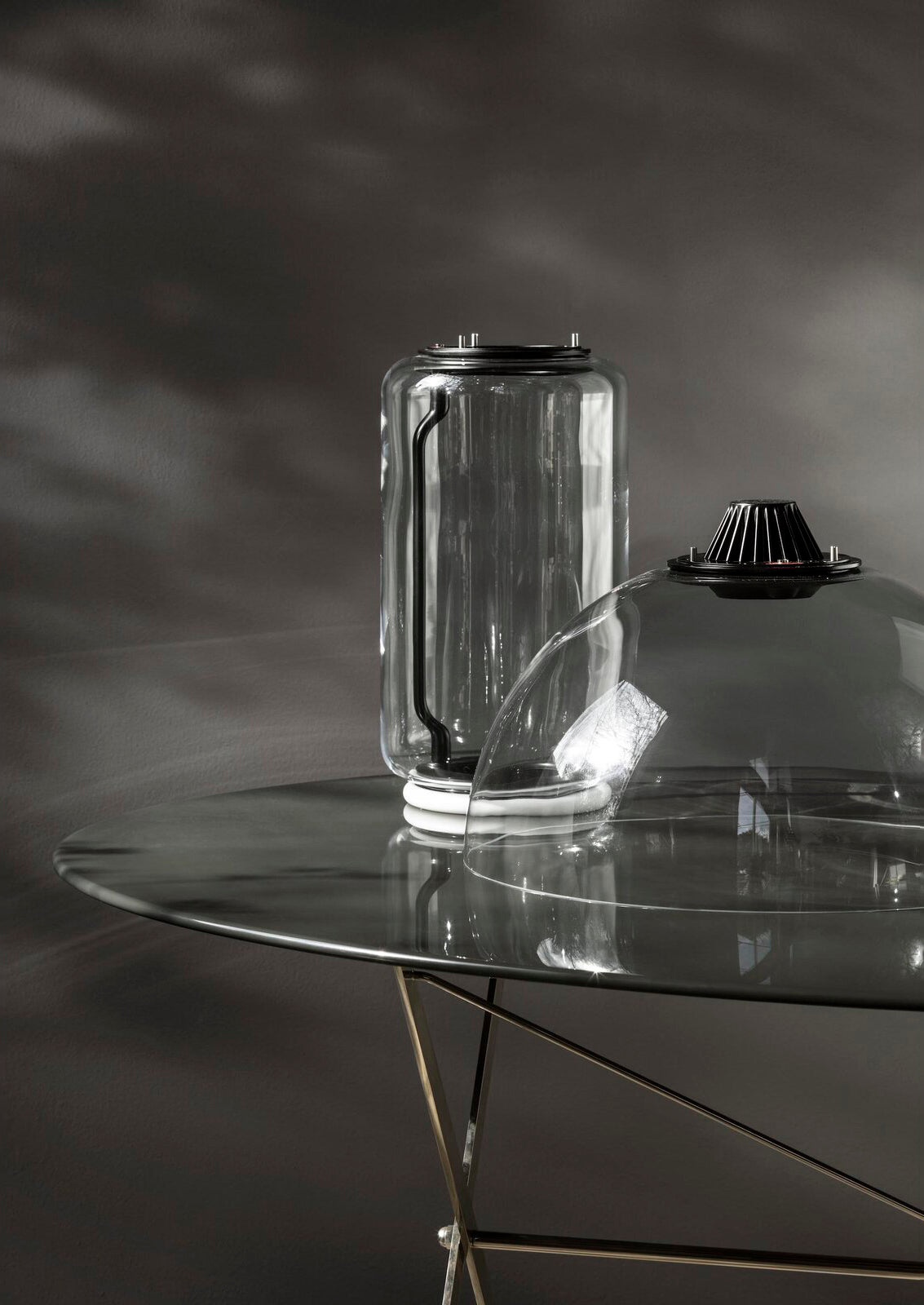 Close view of one glass cylinder from this Clérachic pendant fitted with its black LED cap on a glass table.