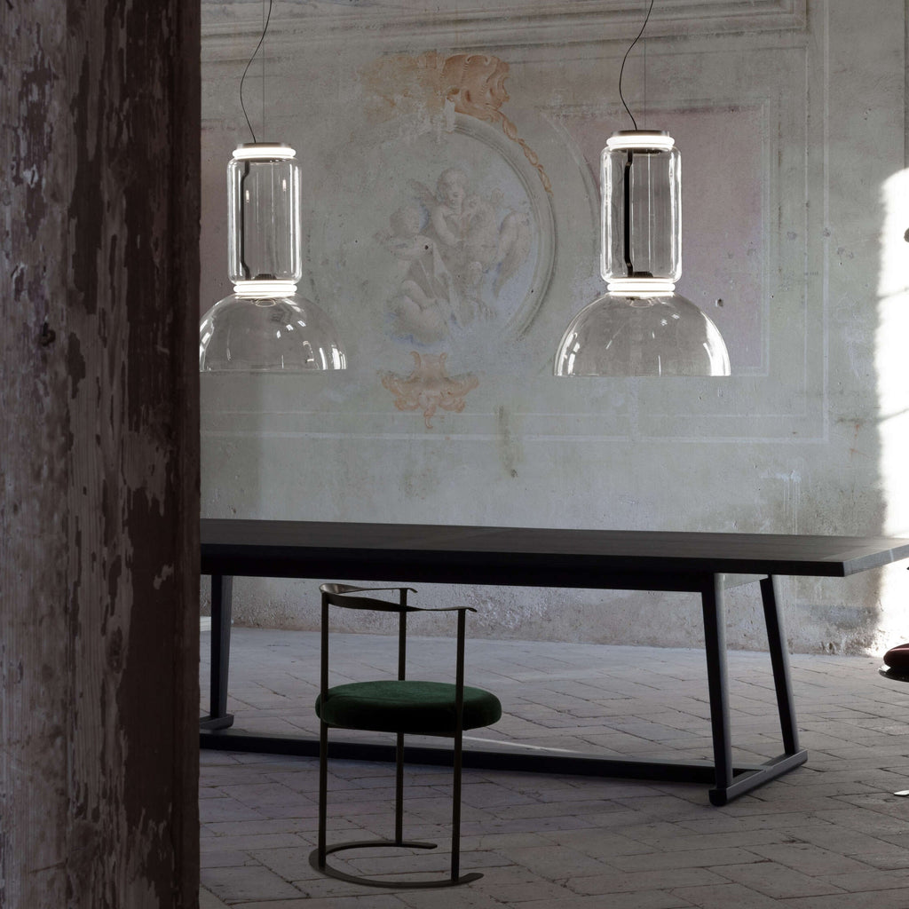 Two small square-edged Clérachic pendants hang above a stone bench and green stool in a weathered courtyard.