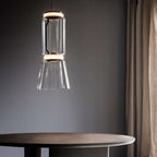 Close view of this Clérachic pendant's cylinder-and-cone shade glowing warm above a round table.
