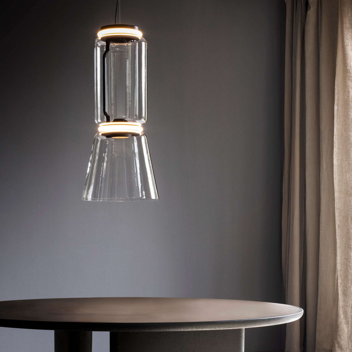 Close view of this Clérachic pendant's cylinder-and-cone shade glowing warm above a round table.