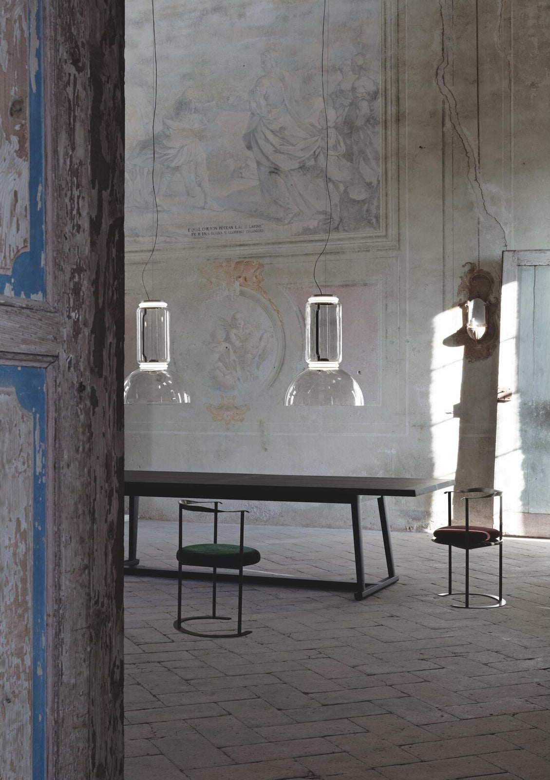 Two small square-edged Clérachic pendants hang above a courtyard table beside a stone stairway.