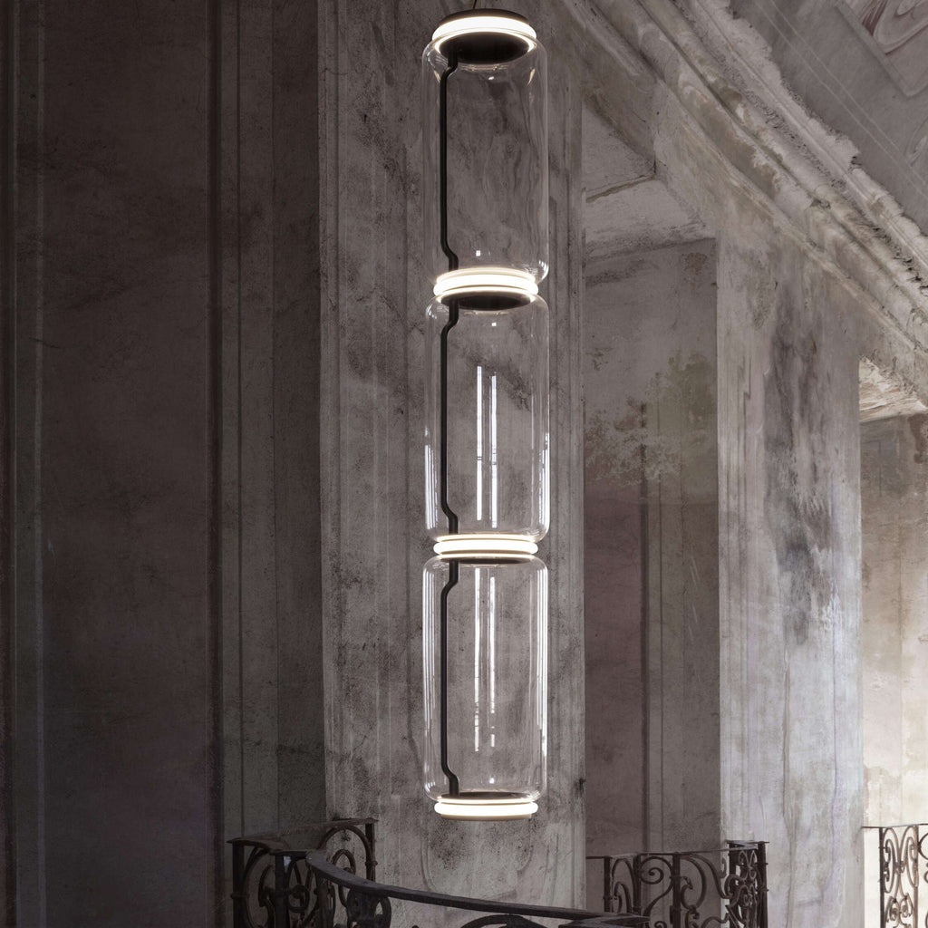 Close view of a three-cylinder stack from this Clérachic pendant beside a weathered stone pillar.