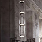 Close view of a three-cylinder stack from this Clérachic pendant beside a weathered stone pillar.