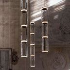 Close view of two cylinder stacks from this Clérachic pendant against a shadowed fresco wall.