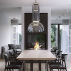 This Clérachic pendant's large dome-shaped shade hangs above a wood table beside a lit fireplace.