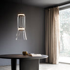 This Clérachic pendant's tapered clear-glass shade glows warm against a dark wall beside a floor-length curtain.