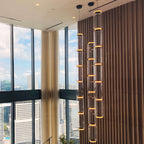A long vertical cluster of this Clérachic pendant's warm-toned cylinders lights a floor-to-ceiling window bay.