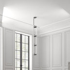 A stack of four unlit cylinders from this Clérachic pendant hangs in a white-panelled corridor near a window.