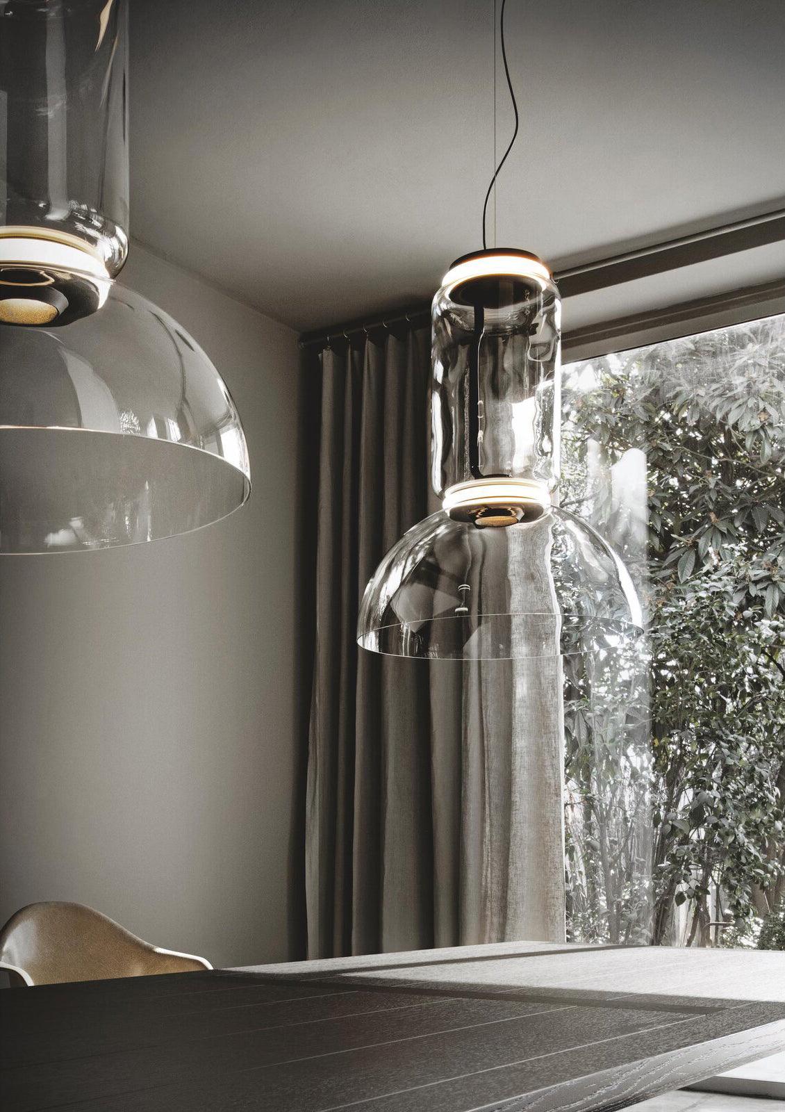 Close view of two dome-shaped Clérachic pendants side by side near a curtained window.