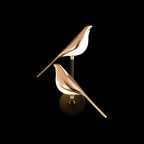 Black and rose gold bird-shaped Nomi wall lamp glowing softly
