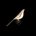Nomi bird-shaped wall lamp in black and rose gold mounted on a wall