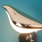 Nomi wall lamp lit beside framed art on a styled wall