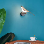 Bird-shaped Nomi wall lamp glowing in a warm room setting