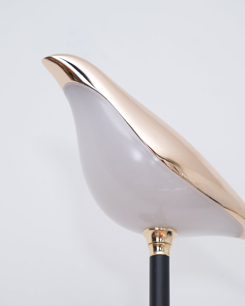 Nomi wall lamp glowing softly to highlight its decorative bird