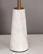 Close-up of the full faceted marble base of the Clérachic table lamp, veining visible against a plain wall.