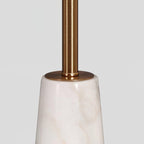 Close-up of the Clérachic table lamp's polished gold stem meeting its faceted marble base.