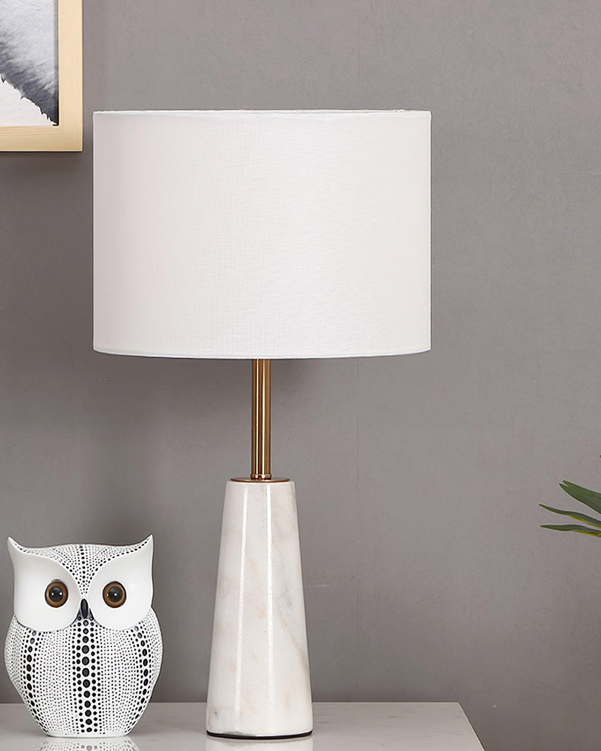 Clérachic lamp beside the same ceramic owl figurine, photographed in daylight against a grey wall.