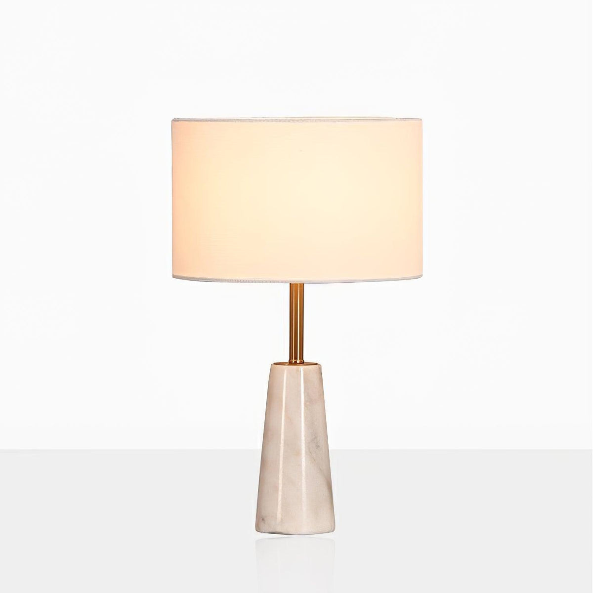 Clérachic lamp with its drum shade glowing warm, cropped closer against a soft grey studio gradient.