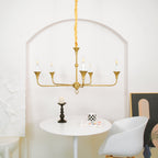 Candle chandelier hanging over a table with candle-style bulbs glowing