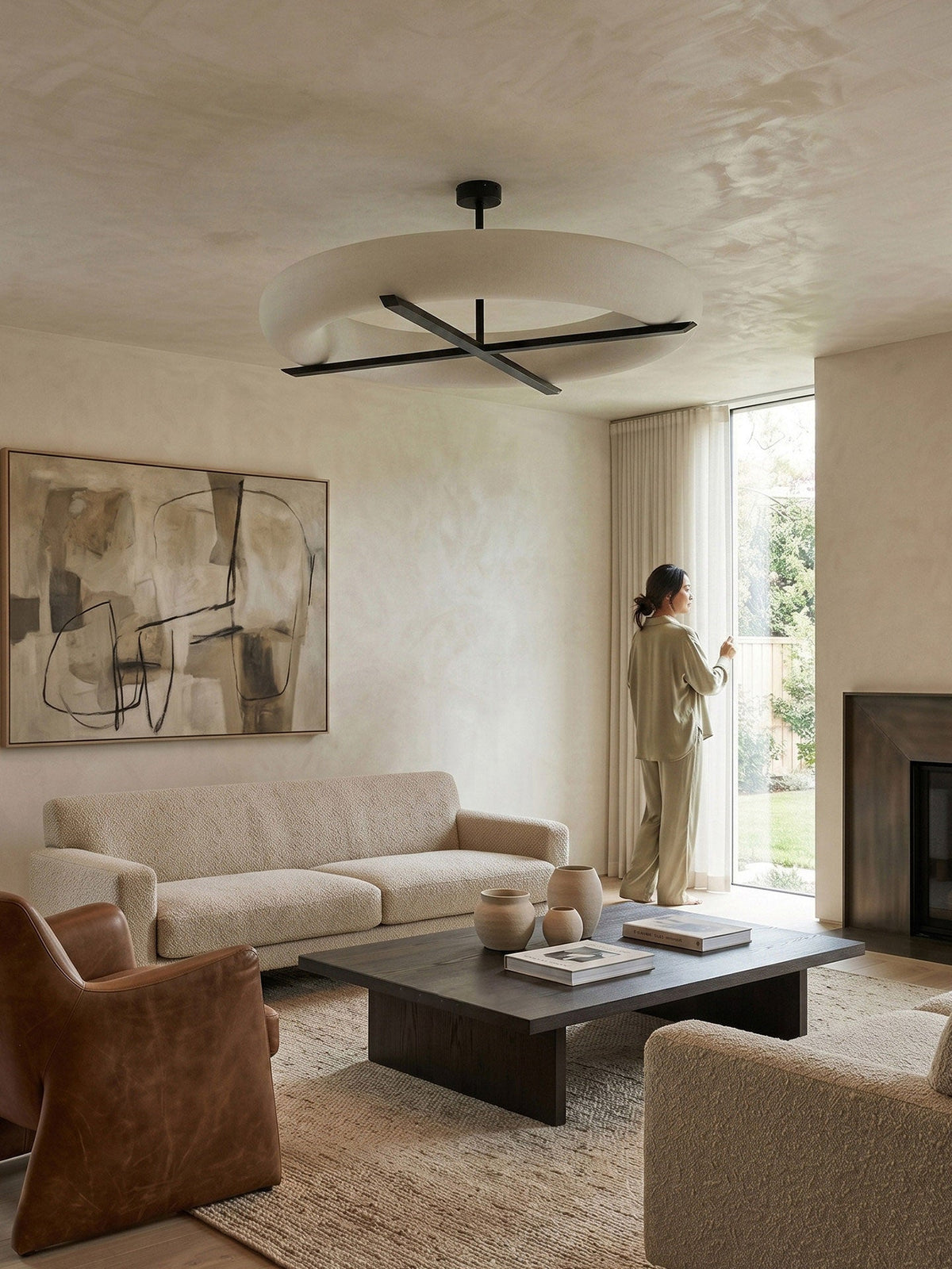In a sunlit living room with a leather armchair and fireplace, this Clérachic ceiling light in black glows overhead.