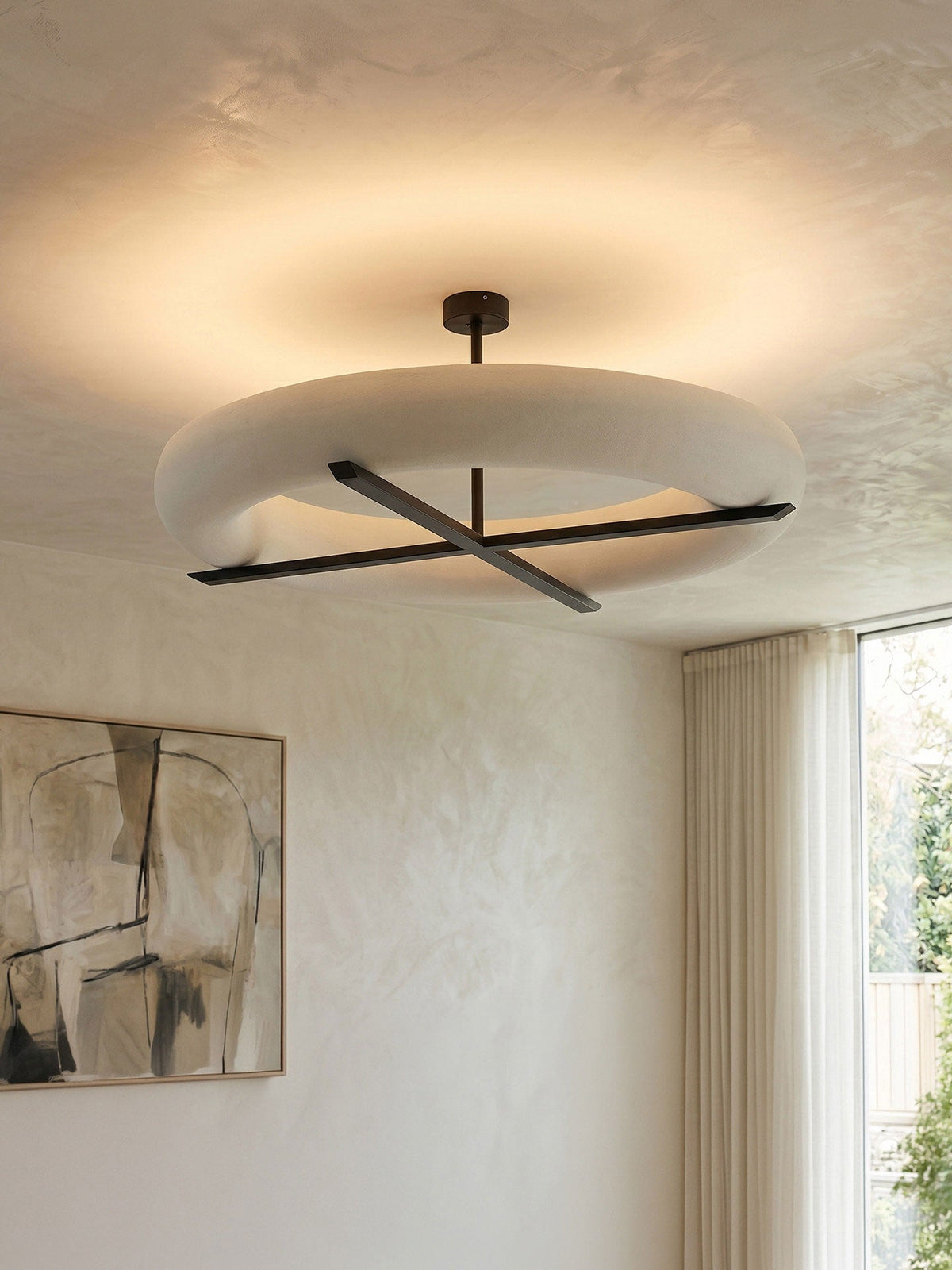 Hung in a plaster-textured room, this Clérachic ceiling light in black glows beside a window and framed sketch.