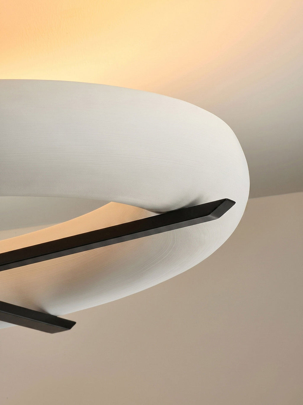 Close-up of the tapered black stem tip on this Clérachic ceiling light, set against its warm-lit white shade.