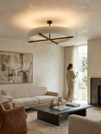 In a living room with a dark coffee table and leather chairs, this Clérachic ceiling light in black glows above.
