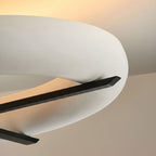 Close view of the crossed black stem on this Clérachic ceiling light, set against its curved white shade.