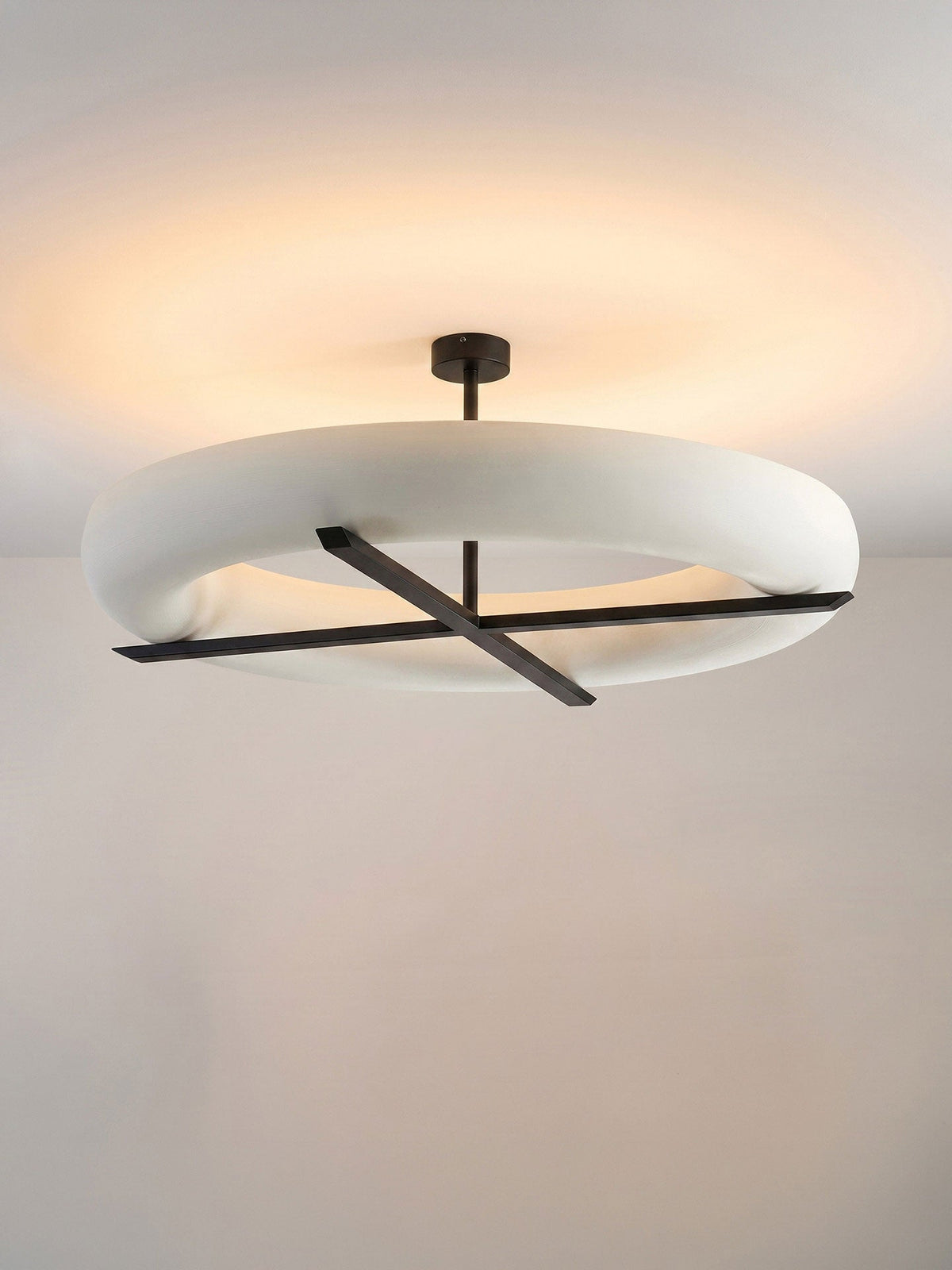 Front view of this Clérachic ceiling light in black, its warm glow spreading evenly across a plain white ceiling.