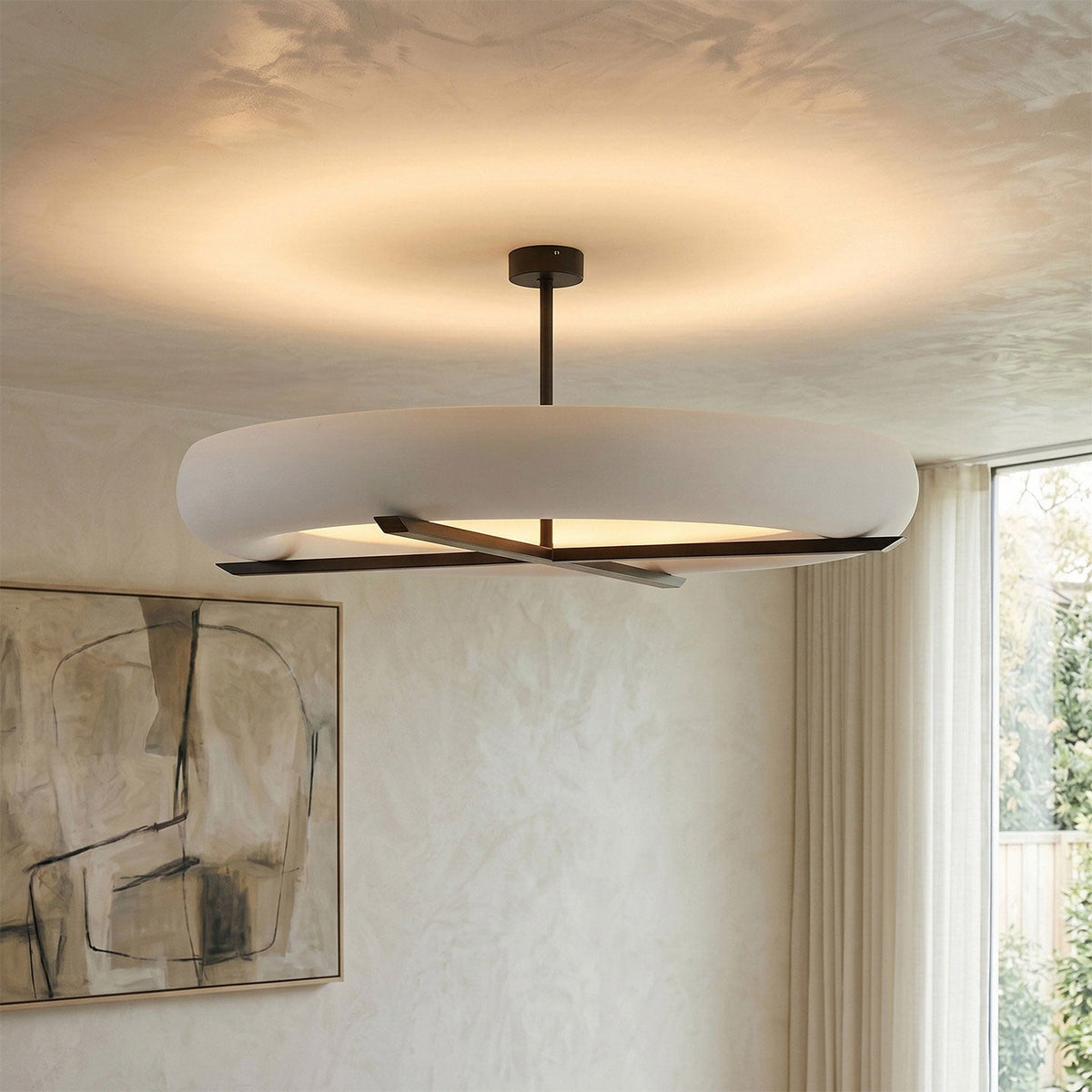 In a room with textured plaster walls and framed sketches, this Clérachic ceiling light in black lights the space above.