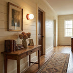 Nuvol glass globe wall lamp lit warmly in a hallway