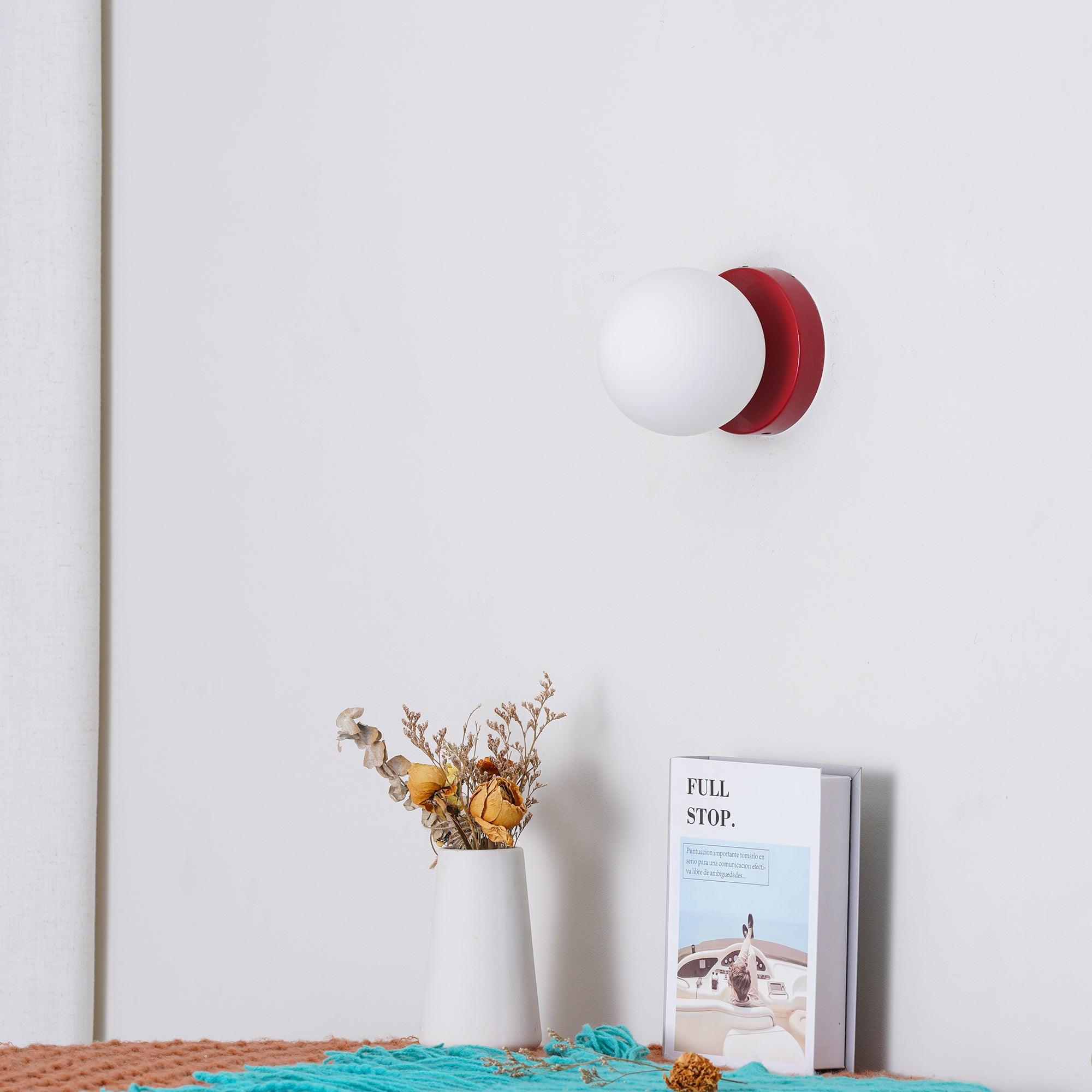 Black Nuvol wall lamp with white glass globe glowing softly