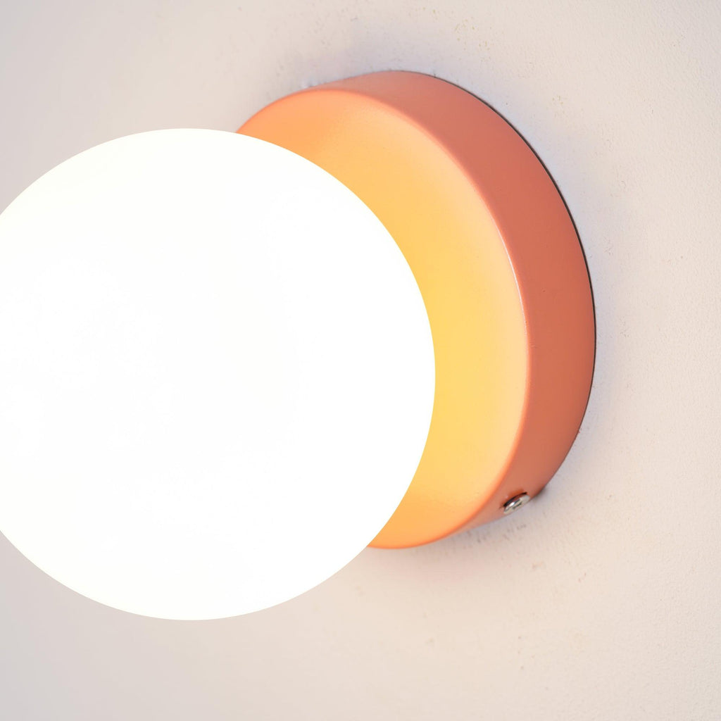 Nuvol wall lamp with colored base and white globe on a wall