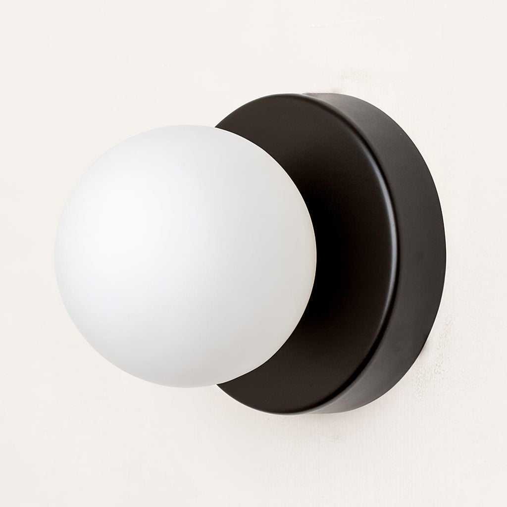 Compact Nuvol glass sconce glowing in a cozy reading corner