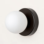 Compact Nuvol glass sconce glowing in a cozy reading corner