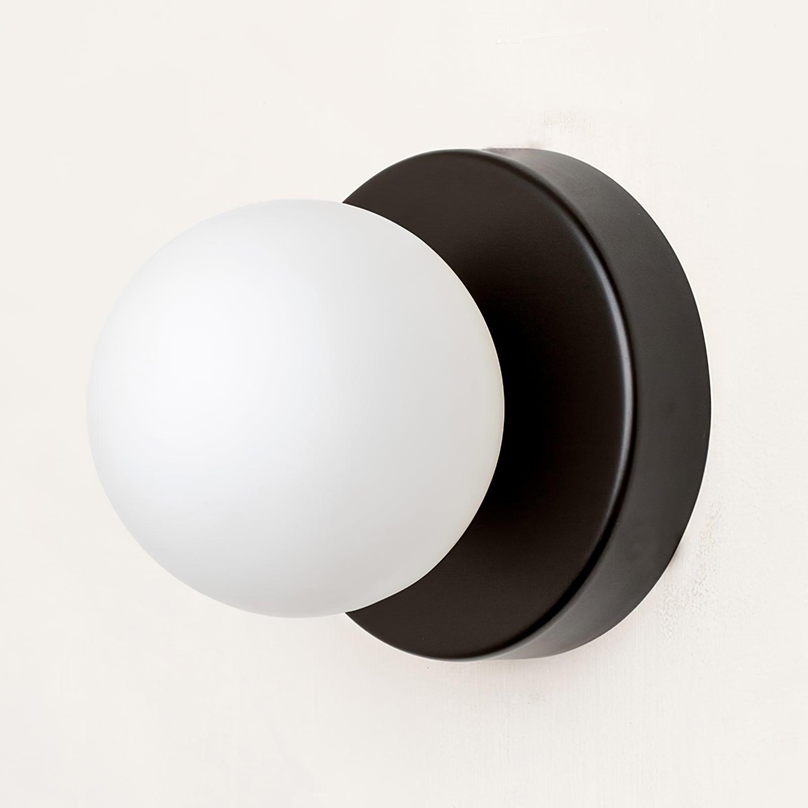 Compact Nuvol glass sconce glowing in a cozy reading corner