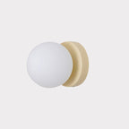 White glass globe Nuvol wall lamp glowing softly on a wall