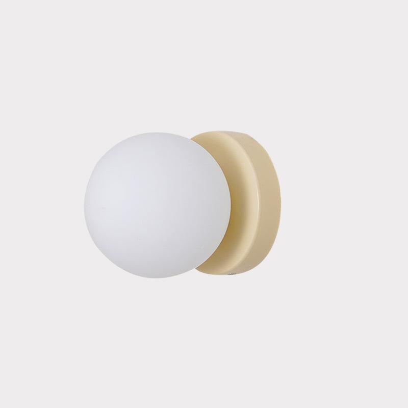 White glass globe Nuvol wall lamp glowing softly on a wall