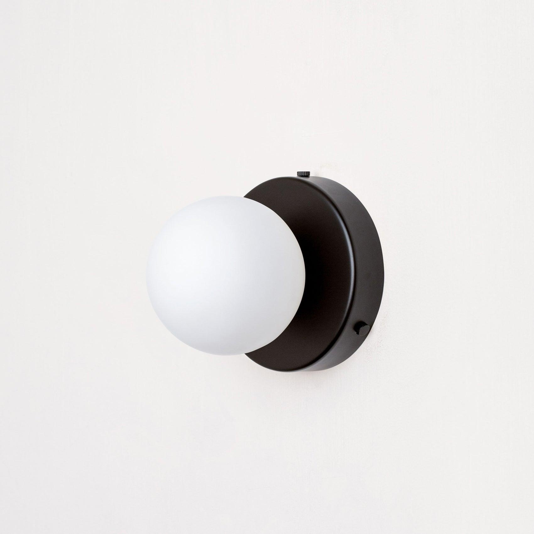 Green Nuvol wall lamp mounted on a neutral interior wall