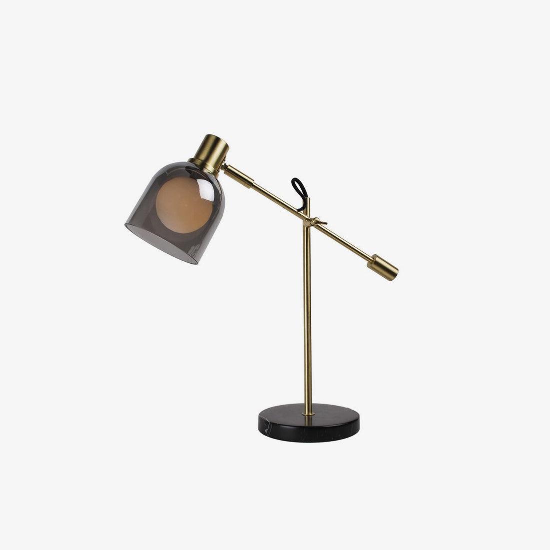 Clérachic brass table lamp with its smoke-glass shade tilted down, photographed close-in against a plain white background.
