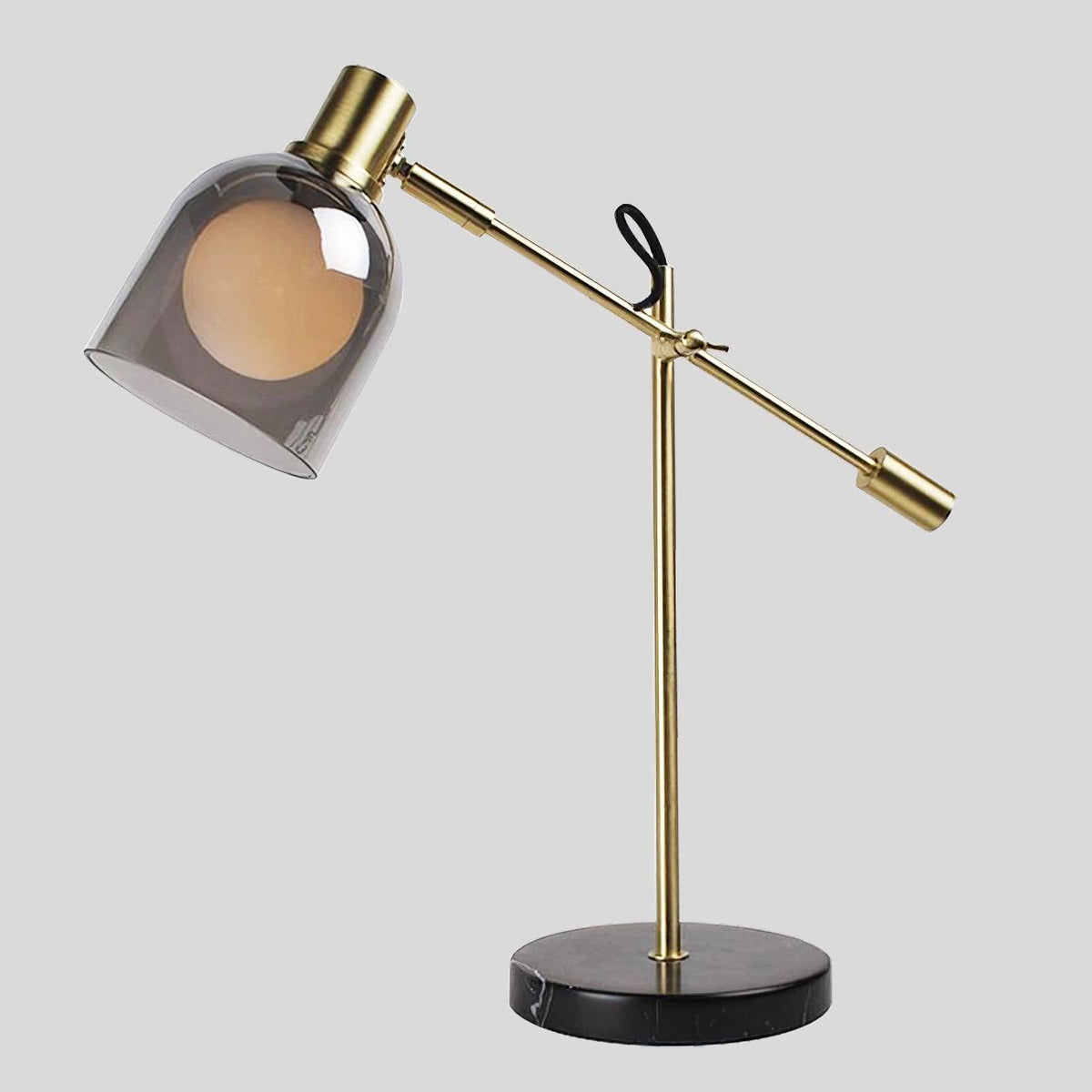 Clérachic brass table lamp on its black marble base, angled toward the camera against a plain light grey background.