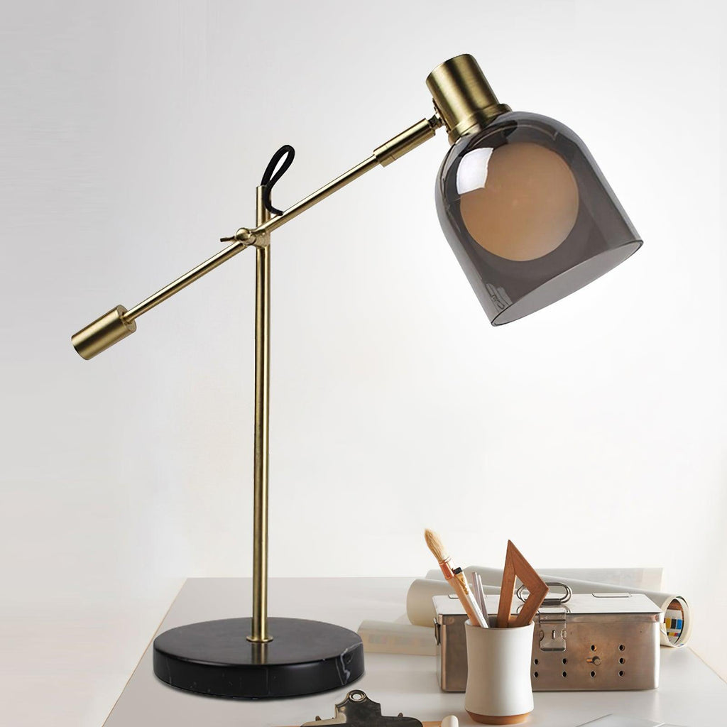 Clérachic brass table lamp on a white desk next to rolled papers and a pen holder, close to a wall power socket.