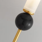 Macro detail of a Clérachic wall light's brass collar where the frosted shade meets the black marble orb, veining visible.