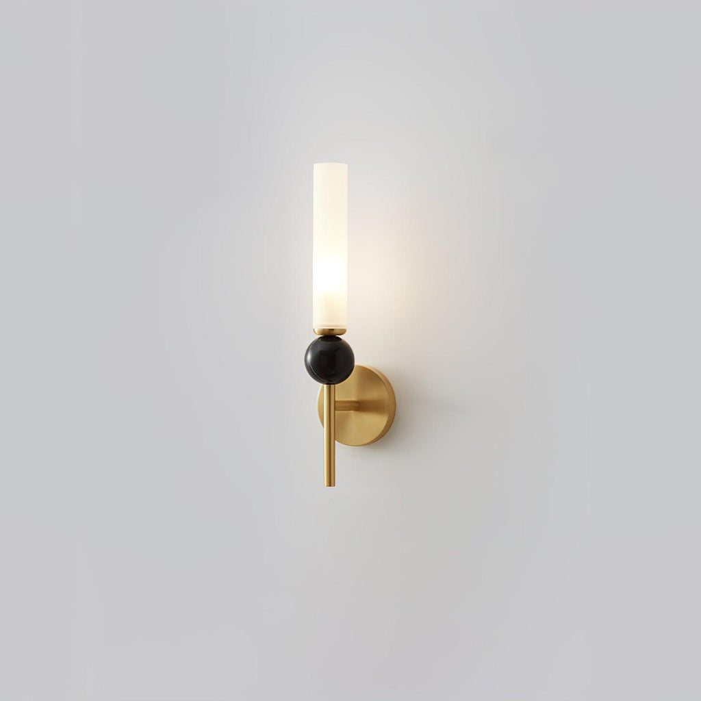 A Clérachic brass-arm wall sconce with a black marble orb, lit and shown front-on against a plain grey studio background.