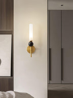 A Clérachic brass wall sconce lit beside a wardrobe door and a framed abstract print in a neutral bedroom corner.