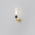 A Clérachic brass-arm wall sconce with a black marble orb, shown front-facing and lit against a plain grey background.