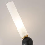 Macro shot of a Clérachic wall light's frosted cylindrical shade tilted atop a black marble orb, showing the stone's natural veining.