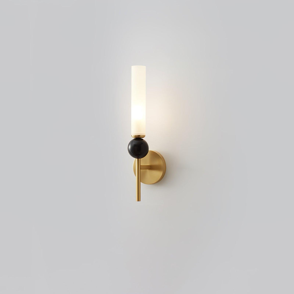 A Clérachic brass-arm wall sconce with a black marble orb, lit and photographed alone against a plain grey background.