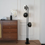 Clérachic floor lamp with its top ring lit, angled beside a wooden chest of drawers with an orchid in a black vase.