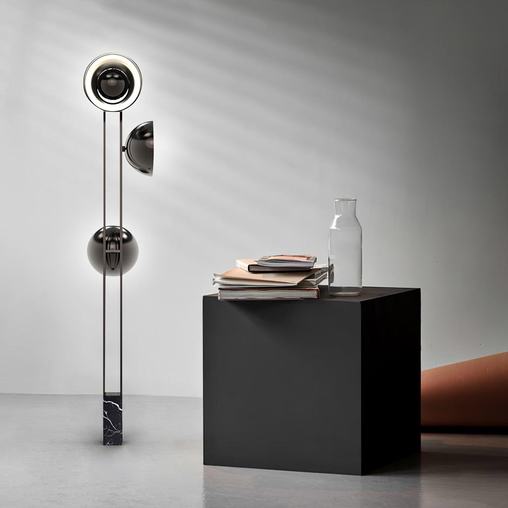 Clérachic three-light floor lamp beside a black cube side table holding a glass vase and stacked magazines.
